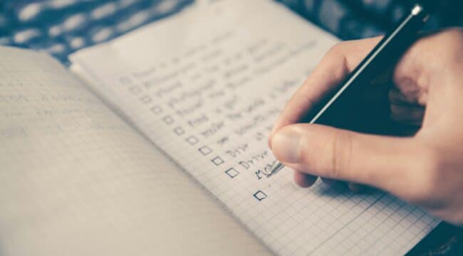 person writing bucket list on book